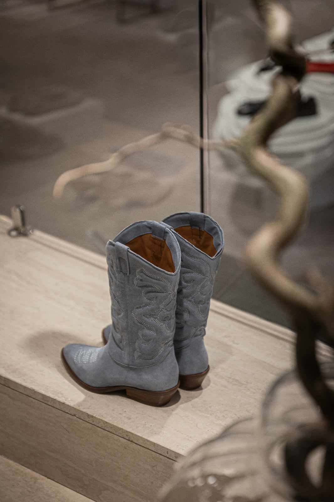 Pair of blue cowboy boots on a wooden surface with a reflective background