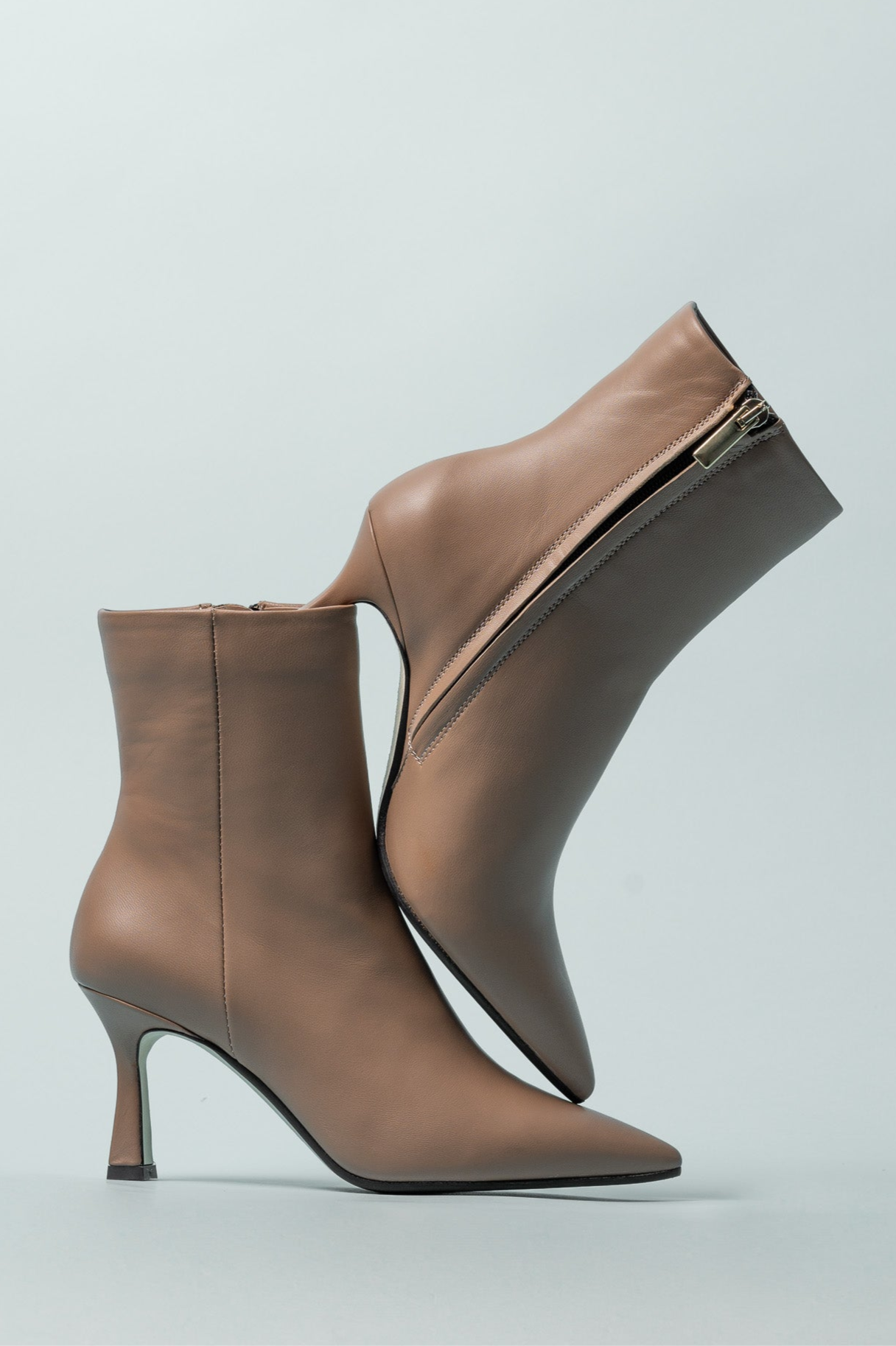 Pair of brown ankle boots with high heels on a light gray background