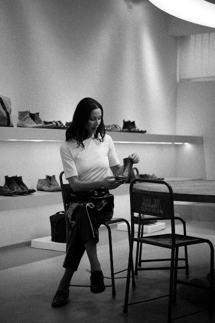 Woman sitting on a chair in a shoe store looking at her phone.