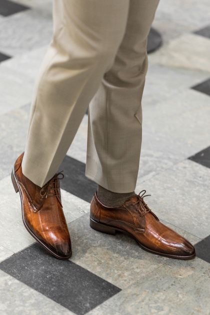 Brown dress shoes and beige pants on a checkered floor