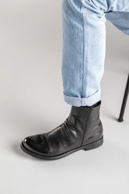 Black ankle boot worn with light blue jeans on a neutral background
