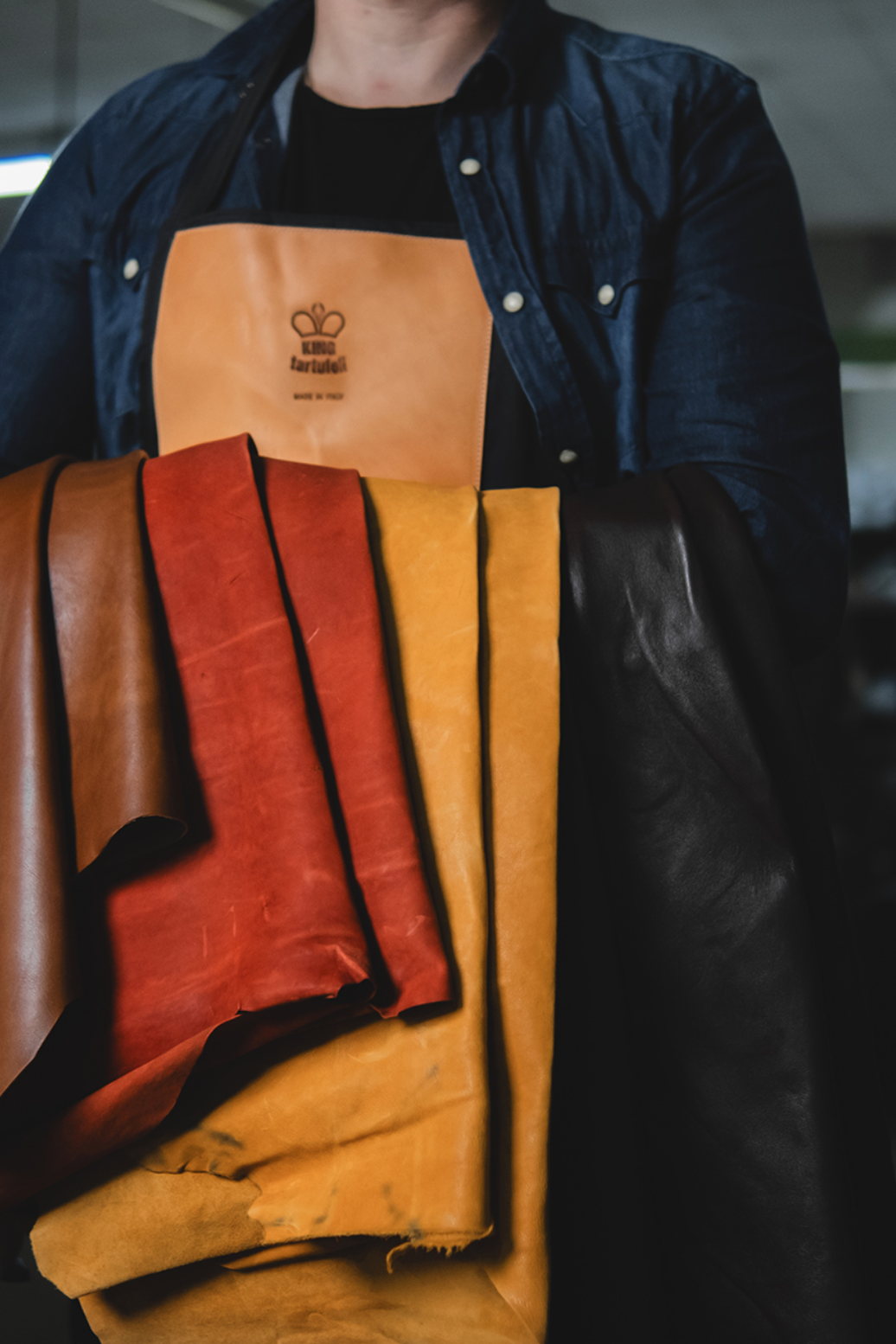 Person holding leather samples with a brand logo in the background
