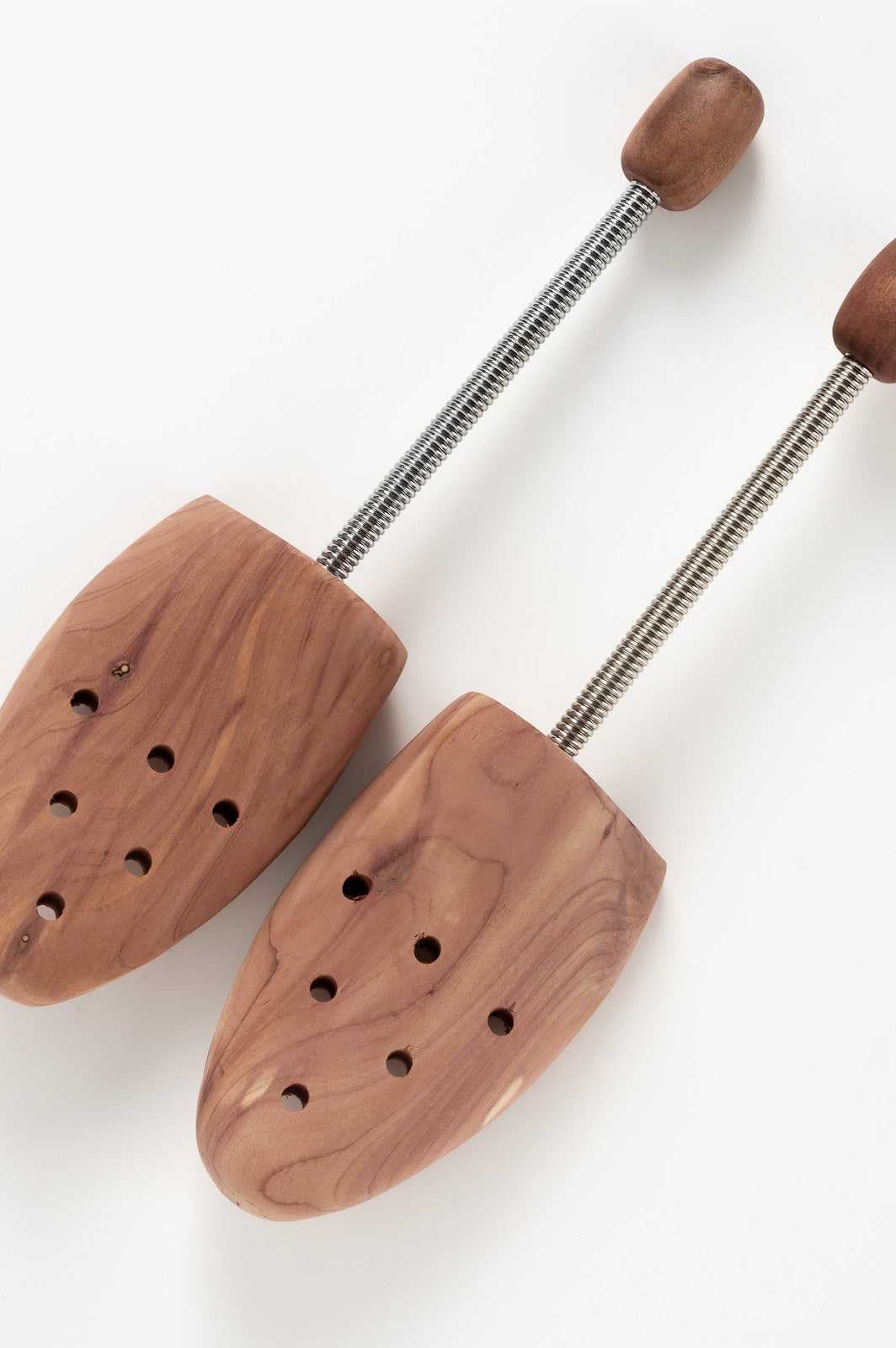 Wooden shoe trees with metal rods on a white background