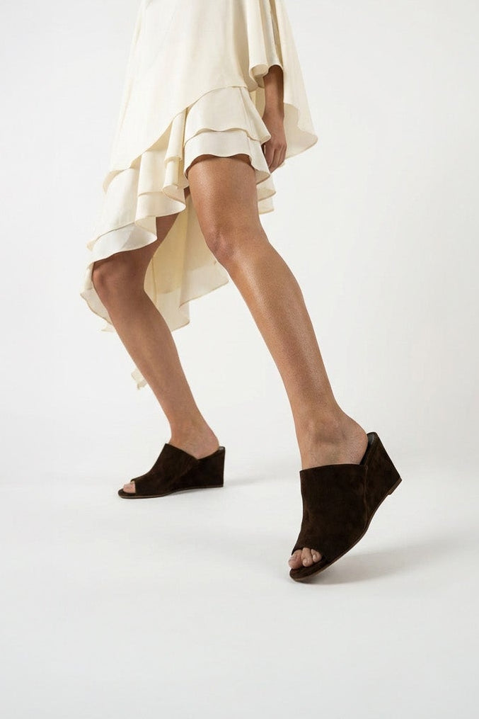 Woman wearing a white dress and black shoes on a light gray background
